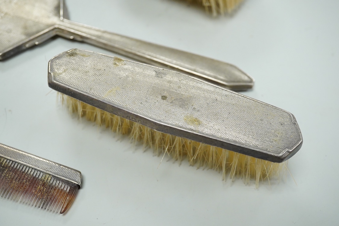 An Elizabeth II engine turned silver Art Deco style four pieced dressing table mirror, brush and comb set, W.I. Broadway & Co, Birmingham, 1961/63/65, mirror 27.8cm.